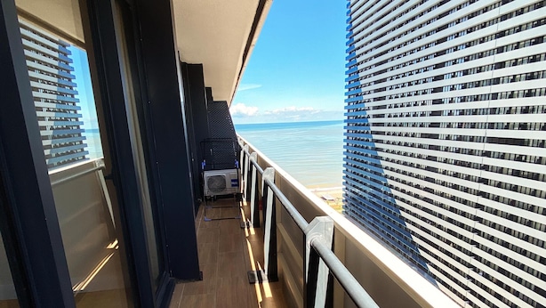 A corridor with a view of the sea and a building with horizontal windows. - Orbi City C Block 2-room Apt 27fl Sea-mount View (Batumi)