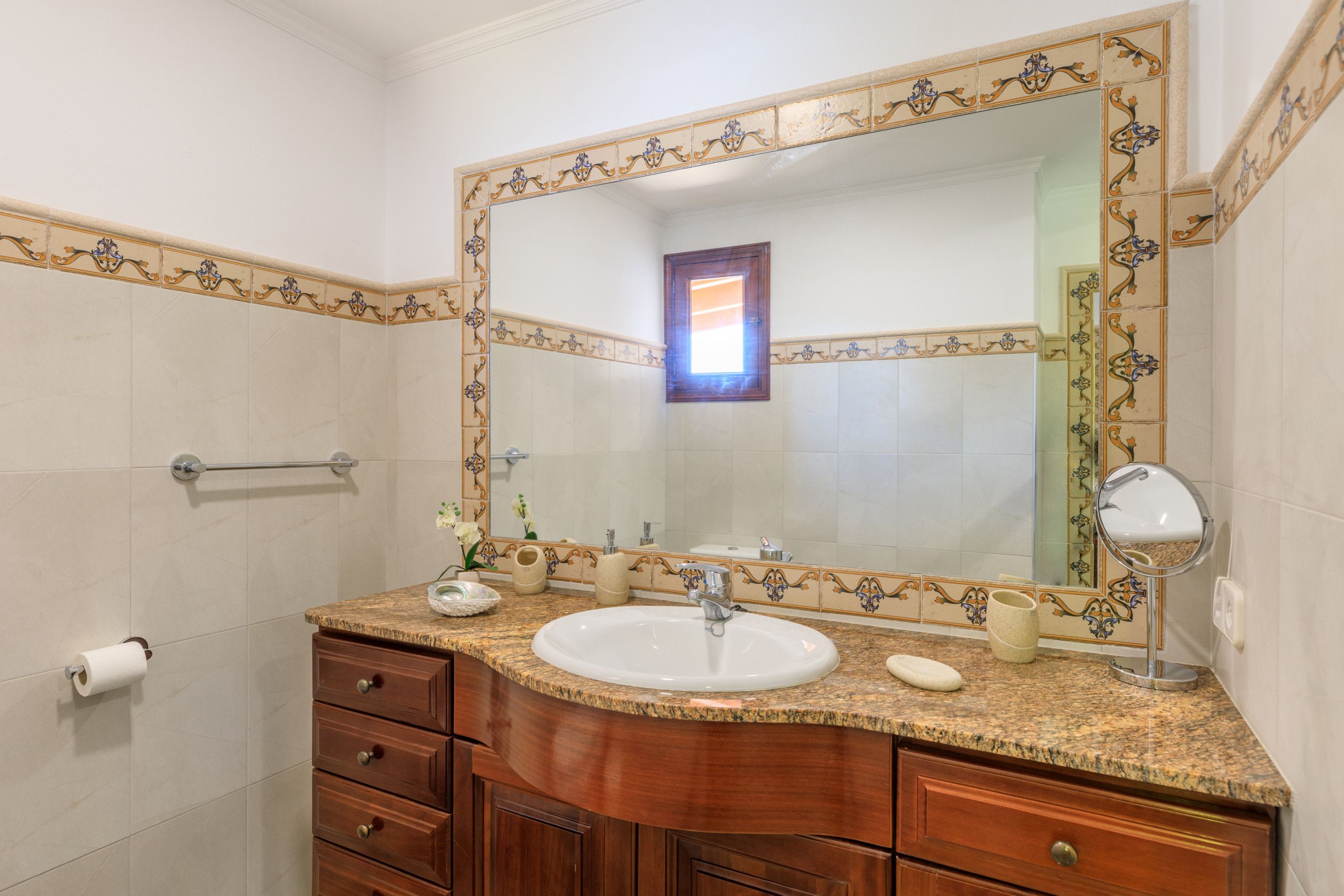 A bathroom with a large mirror, a sink, and a vanity with drawers.