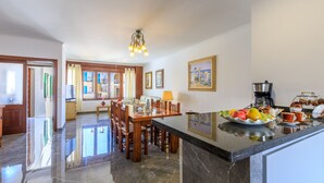 A spacious kitchen with a marble countertop, wooden dining table, and chairs. - Juanito (Puerto Pollensa)