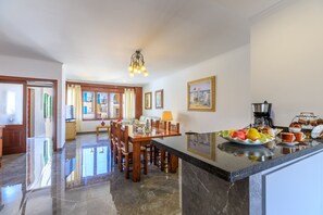 A spacious kitchen with a marble countertop, wooden dining table, and chairs. - Juanito (Puerto Pollensa)