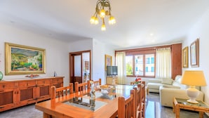 Un salón amplio con una mesa de comedor de madera, un sofá y una televisión.