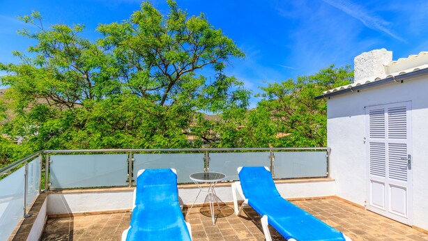 A rooftop terrace with two sun loungers, a small table, and a white door. - Juanito (Puerto Pollensa)