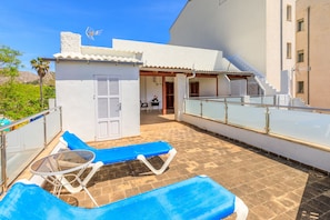 A rooftop terrace with two lounge chairs and a table, a small covered seating area, and a staircase leading to an upper level. - Juanito (Puerto Pollensa)