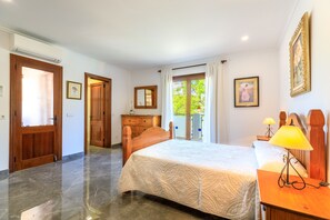 A bedroom with a bed, wooden dresser, and a lamp. - Juanito (Puerto Pollensa)