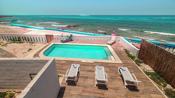 A pool with a view of the ocean, lounge chairs, and a wooden deck. - Hotel La Trigueña (Isla Mujeres)