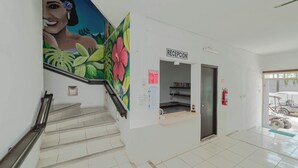 A reception area with a staircase leading to an upper floor, a fire extinguisher, and a sign indicating the reception. - Hotel La Trigueña (Isla Mujeres)