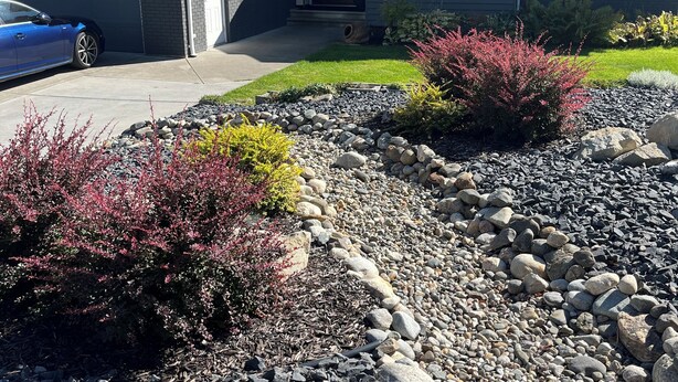 A residential house with a garage, solar panels, and a driveway with a rock and gravel border.