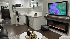 A modern living room with a fireplace, a flat-screen TV, and a round coffee table with decorative items.