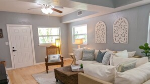Un salon avec un canapé beige, une table basse en bois et un ventilateur de plafond.