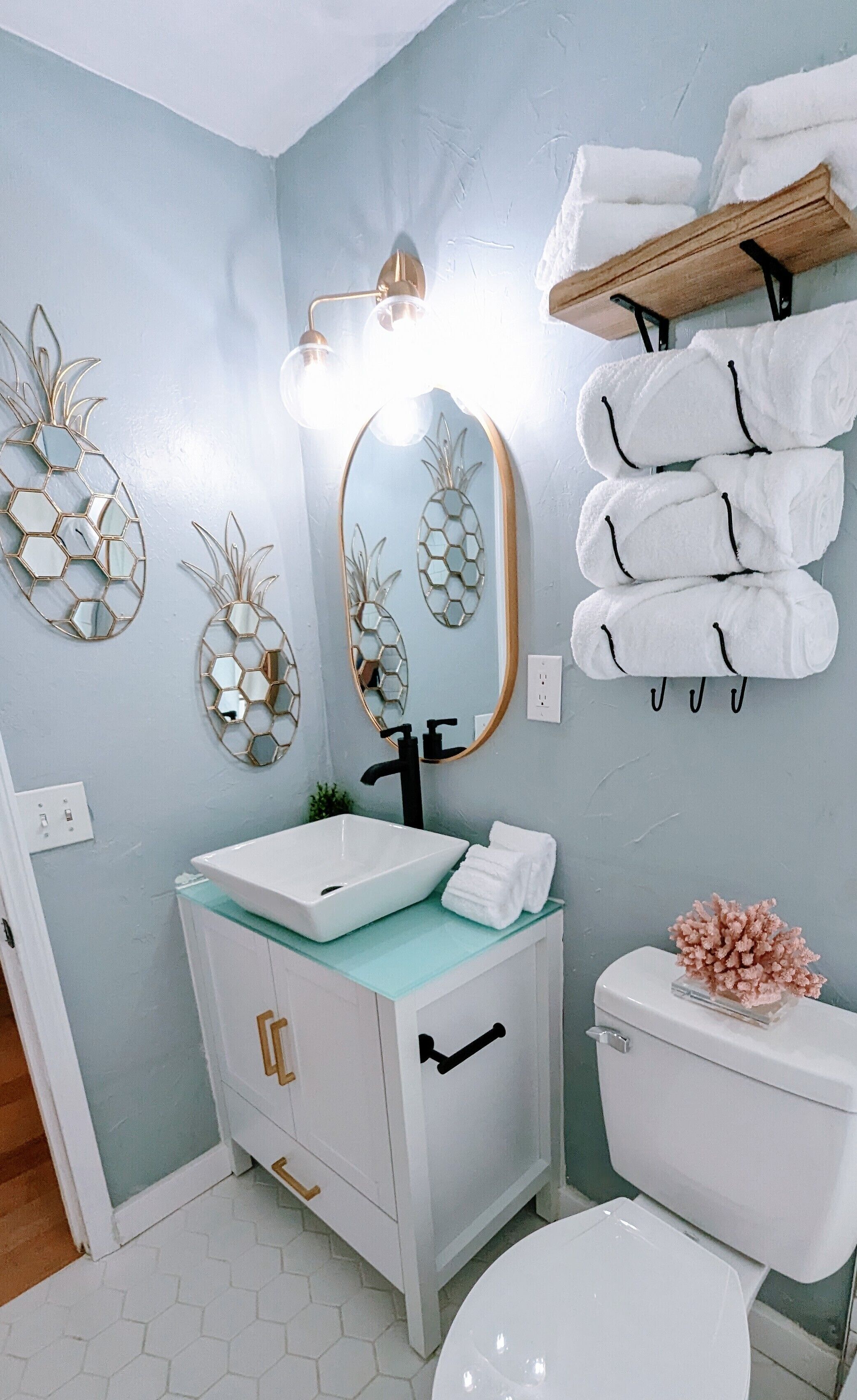 A bathroom with a white sink, a mirror with lights, towels on a rack, and a toilet.