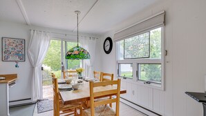 A dining area with a wooden table, chairs, a stained glass window, and a clock on the wall. - 'Summer Place' A Vibrant Rental on Lake Huron (Tawas City)