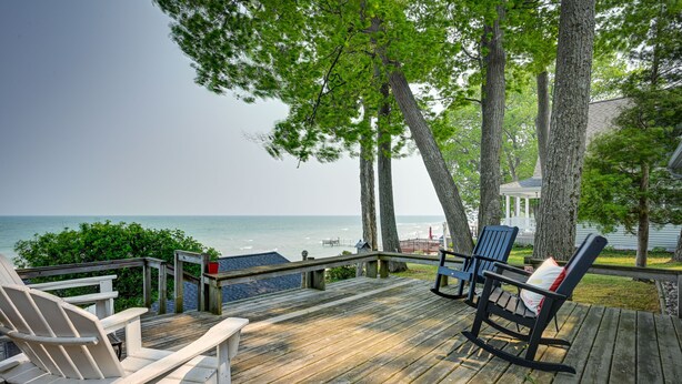 A wooden deck with two Adirondack chairs, a gazebo, and a view of the ocean. - 'Summer Place' A Vibrant Rental on Lake Huron (Tawas City)