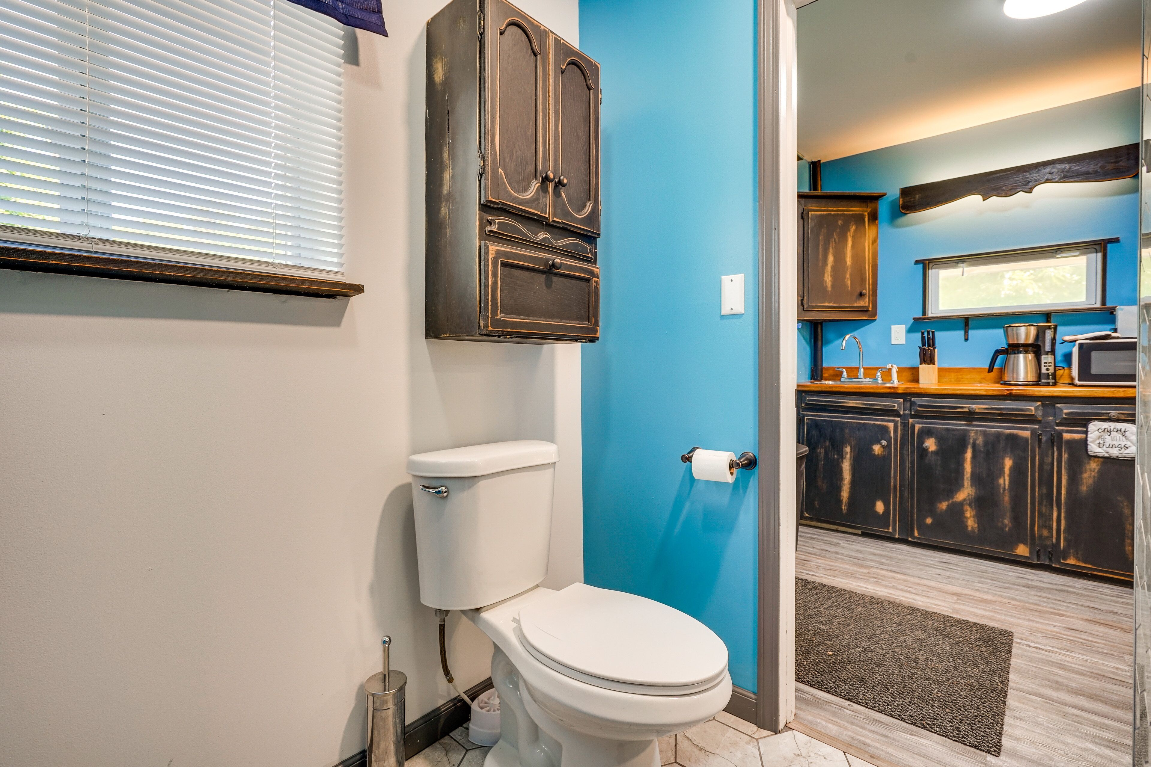 A bathroom with a toilet, a cabinet, and a blue wall.