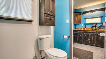 A bathroom with a toilet, a cabinet, and a blue wall.