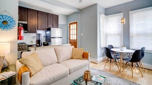 A modern living room with a sofa, coffee table, and dining area. - Charming Ocean City Apartment < 1 Mi to Boardwalk! (Ocean City)