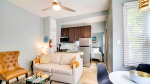 A living room with a sofa, armchair, and coffee table. There is a kitchen in the background with cabinets and appliances. - Charming Ocean City Apartment < 1 Mi to Boardwalk! (Ocean City)
