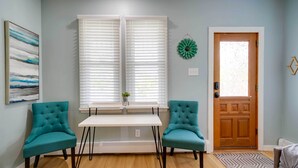 A room with a white table and two teal chairs, a wooden door, and a window with blinds. - Modern Ocean City Getaway: Walk to Boardwalk! (Ocean City)
