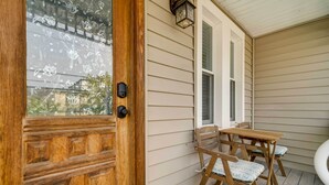 A wooden door with a glass panel, a small porch with a table and chairs, and a window. - Modern Ocean City Getaway: Walk to Boardwalk! (Ocean City)