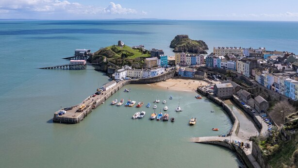 A coastal town with a historic fort, colorful buildings, and a marina with boats.