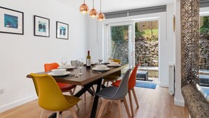 A dining area with a wooden table, colorful chairs, and hanging pendant lights.