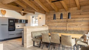 A modern kitchen with built-in appliances, a wooden accent wall, and a central island with seating. - Superior # 2B mit Sauna by Interhome (Uttendorf)