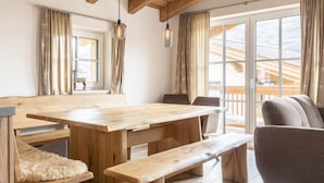 A wooden dining table with benches, a cushioned bench, and a chair in a room with wooden beams and large windows. - Superior # 4D mit Sauna by Interhome (Uttendorf)