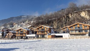 Une rangée de chalets en bois dotés de balcons, se dressant sur un fond de paysage enneigé et de montagnes.