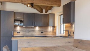 Una cocina moderna con gabinetes oscuros, una encimera de madera y un horno empotrado.