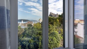 A view from a window overlooking a historic castle on a hill, with lush greenery and a clear sky. - La Vigna Rooms (Ischia)