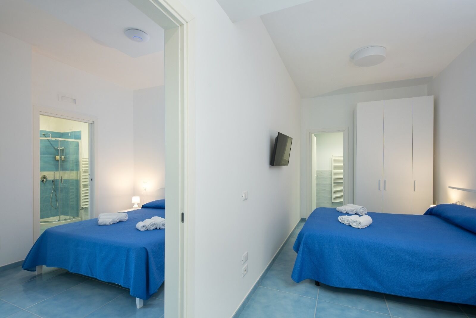 Une chambre d’hôtel avec deux lits, une douche, une télévision et une armoire.
