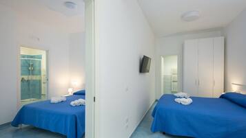 Habitació d'hotel amb dos llits, dutxa, televisió i armari.