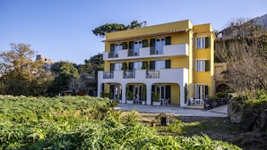 A multi-story yellow building with balconies, surrounded by greenery and a clear sky. - La Vigna Rooms (Ischia)
