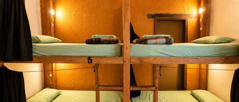 Une chambre avec des lits superposés, des murs en bois et un numéro sur chaque lit.