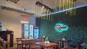 A restaurant interior with wooden tables and chairs, a neon sign, and vending machines. - Amura Hostel  (Antigua Guatemala)