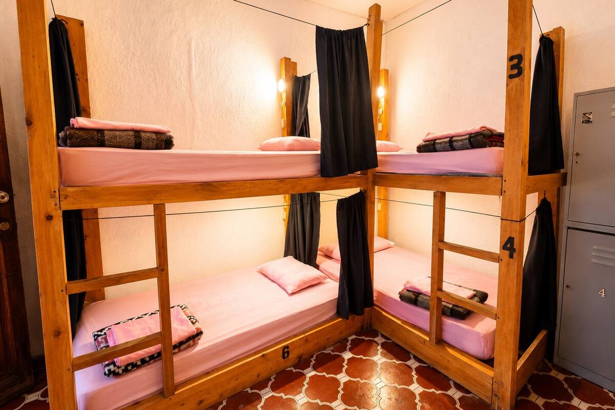 Une chambre d’angle avec des lits superposés, une armoire et un sol carrelé.