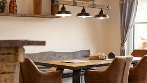 A dining area with a wooden table, four brown upholstered chairs, and three pendant lights. - Premium # 1B mit Sauna by Interhome (Uttendorf)