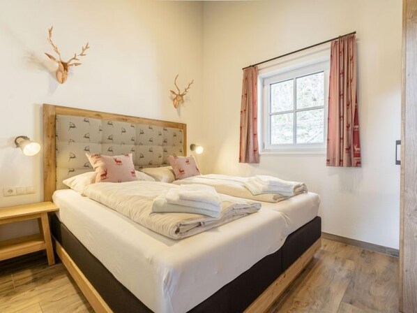 Un lit double avec une tête de lit en bois, deux tables de chevet et une fenêtre avec des rideaux.