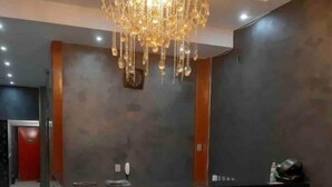 A modern reception area with a dark counter, a chandelier, and a red door in the background. - Apartamento 2010 (Setor Central Goiânia)