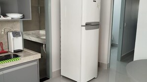 Una cocina moderna con un refrigerador blanco, un horno empotrado y un lavamanos con grifo rojo.
