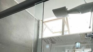 Un baño moderno con cabina de ducha de vidrio, azulejos de mármol y estante empotrado.