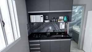 Una cocina moderna con armarios grises, encimera negra y ventana que proporciona luz natural.