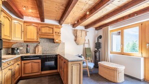 Una cocina con armarios de madera, una estufa y un ventanal con vistas a árboles.