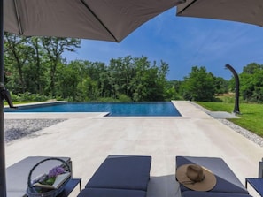 A pool area with lounge chairs and umbrellas, surrounded by greenery. - Rokvilla by Interhome (Motovun)