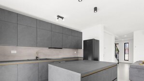 A modern kitchen with grey cabinetry, a central island, and a built-in refrigerator. - Villa Valero by Interhome (Novigrad (Istra))