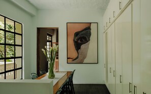 A hallway with a dining table, chairs, a vase with flowers, and a painting on the wall. - Casa Seis Siete (Mexico City)