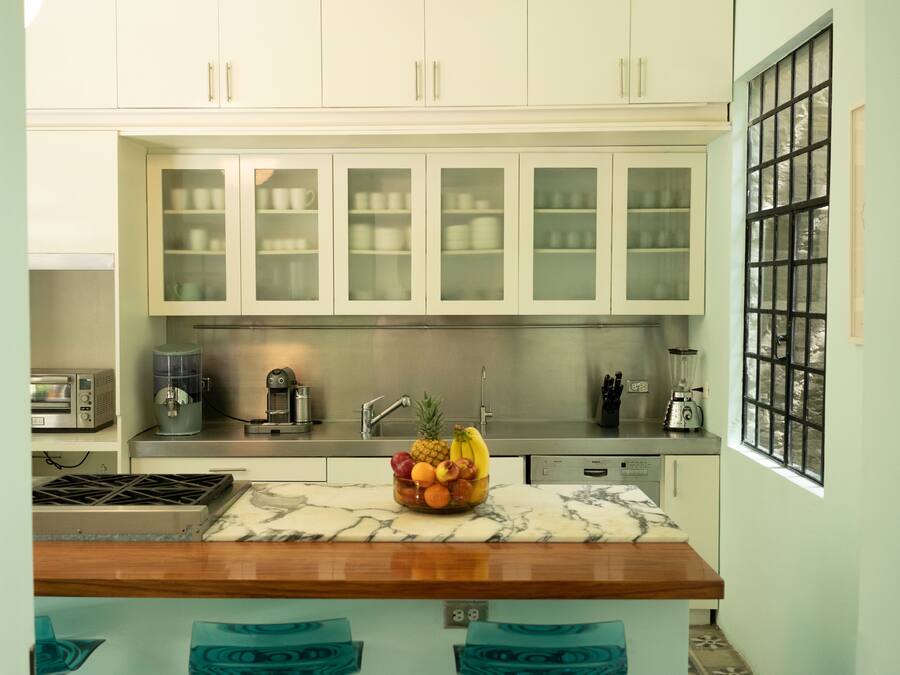 A kitchen with white cabinets, a marble countertop, and a fruit bowl.