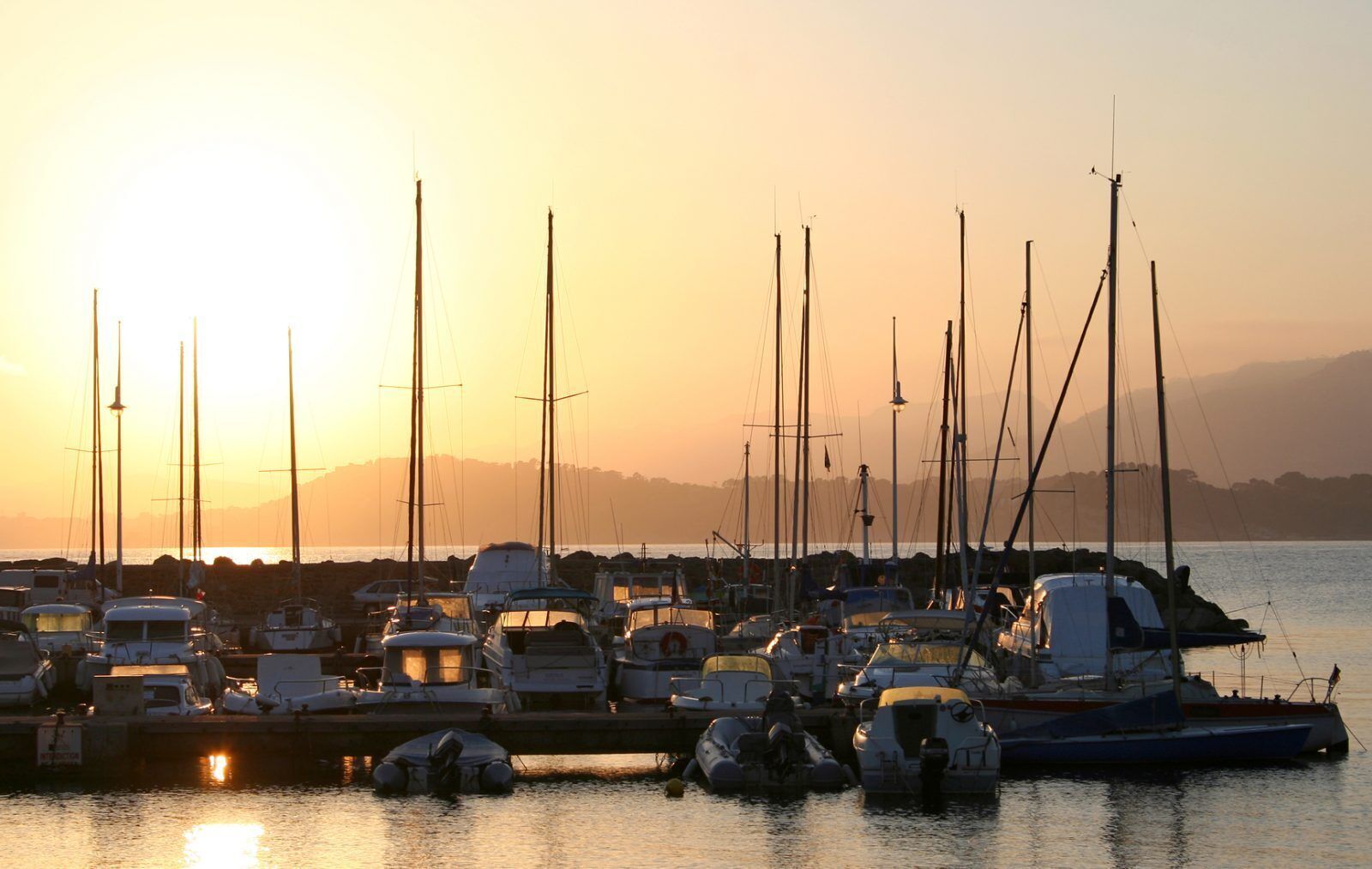 Un puerto deportivo con varias embarcaciones amarradas al atardecer.