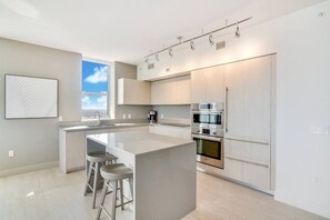 Eine moderne Küche mit einer zentralen Kochinsel, Edelstahlgeräten und einem großen Fenster für natürliches Licht.