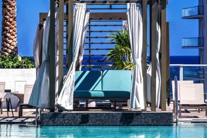 A poolside area with a covered seating area, lounge chairs, and a palm tree. - Condo in Hollywood Beach 3-2 (Hollywood)