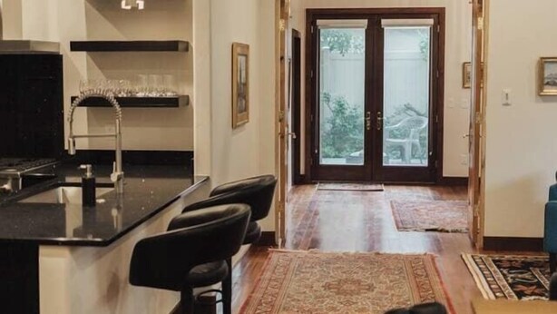 A modern kitchen with a bar area, a dining table with chairs, and a view through a glass door to the outdoors. - Renovated & Modern 8 Guest Stay - Midtown Billings (Billings)